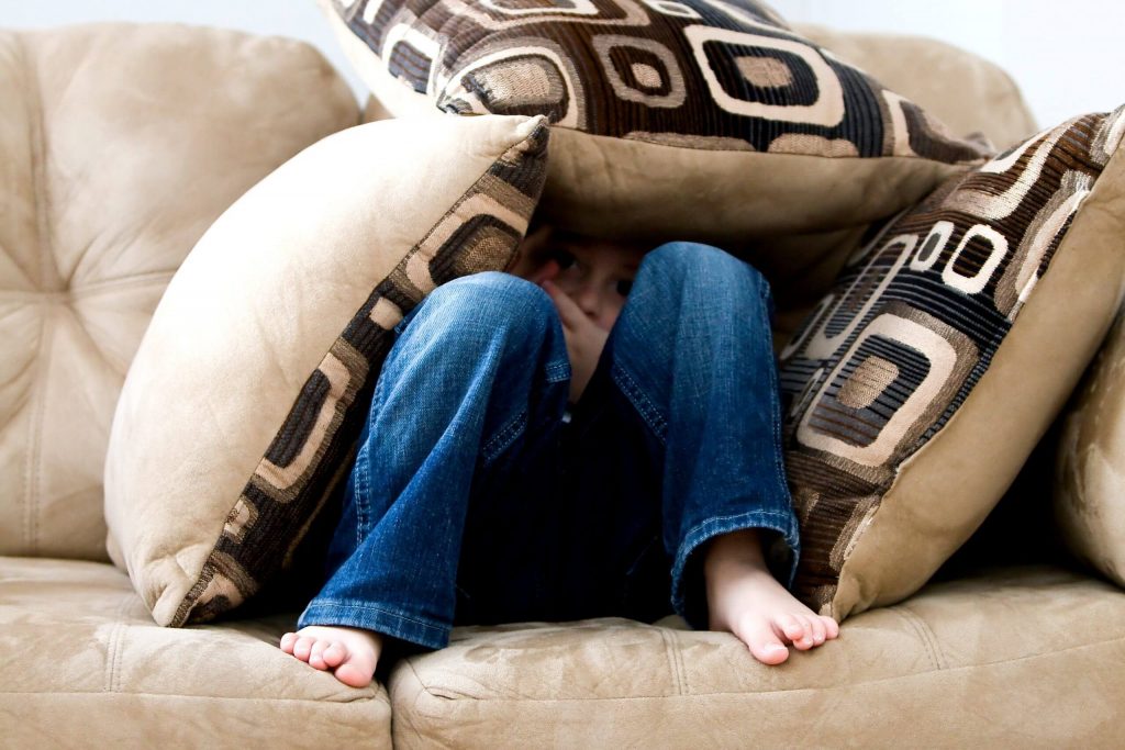 Child Separation Anxiety: A child hides under couch pillows.