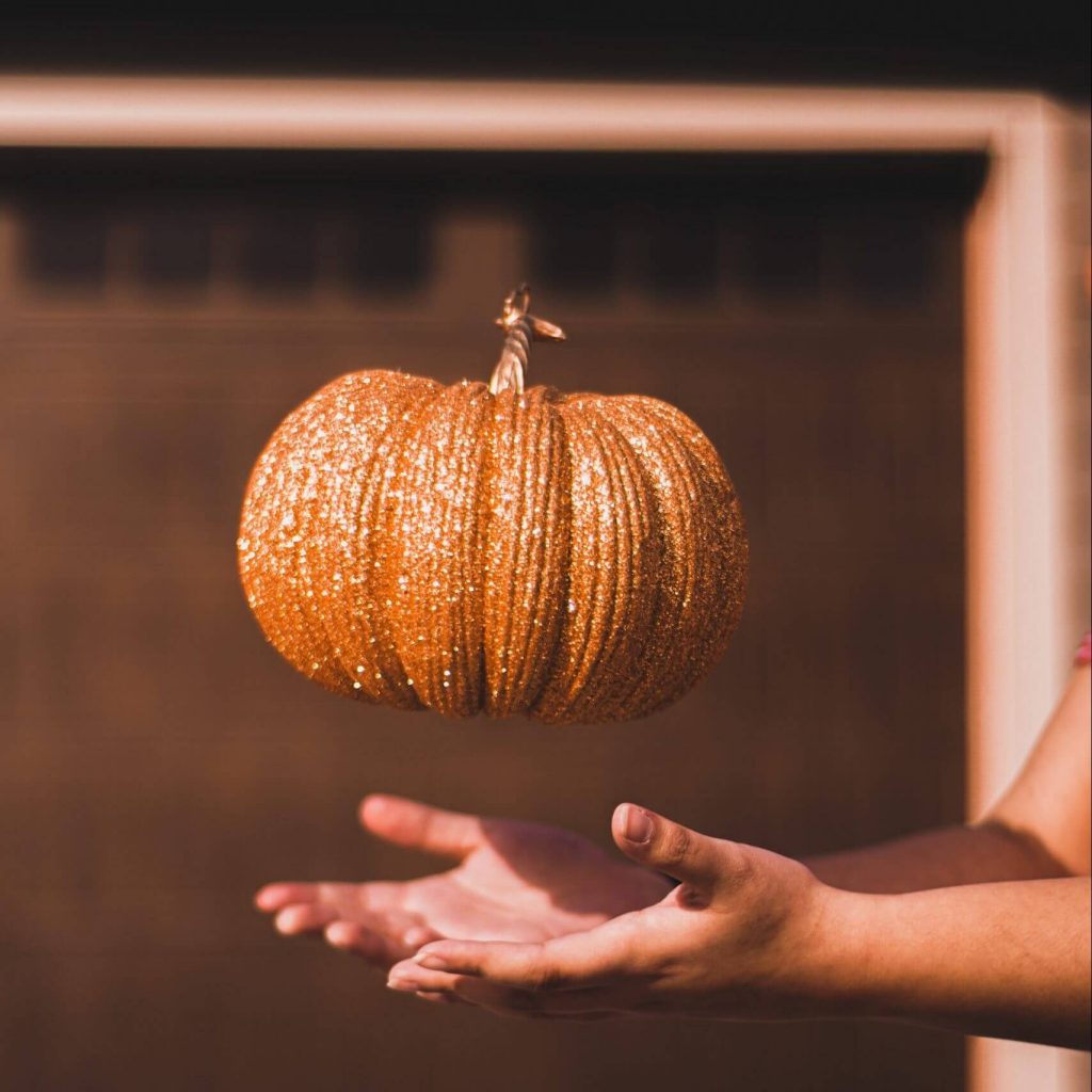 Thanksgiving Crafts For Kids - A person tosses a glittery craft pumpkin in the air.