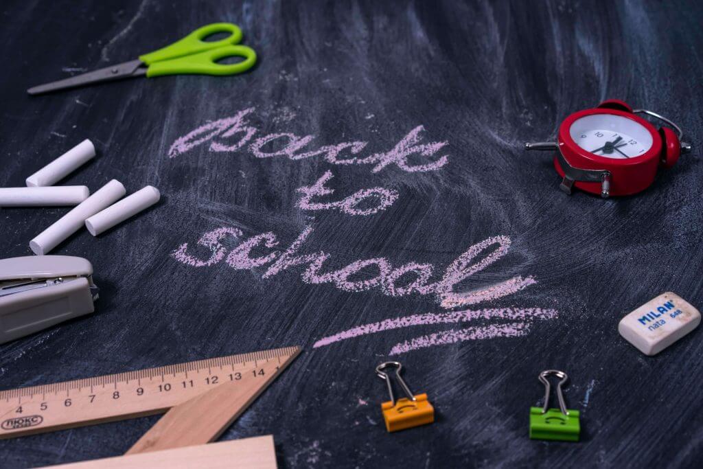 Back to School Tips For Parents - "Back to School" is written in chalk on a blackboard surrounded by various school supplies.