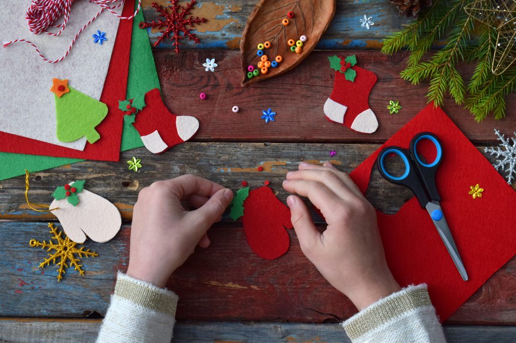 Making of handmade christmas toys from felt with your own hands. Children's DIY concept. Making xmas tree decoration or greeting card. Step 3. Decorate the toy.